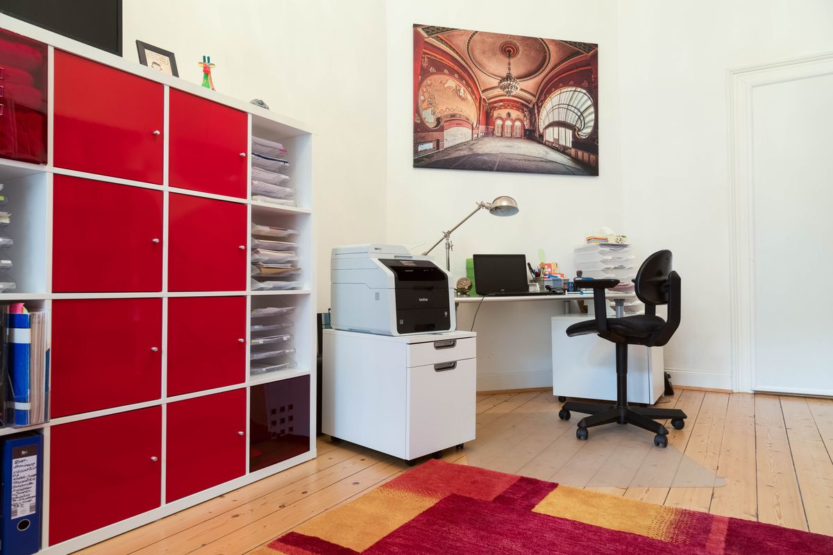 Arbeitsbereich der Praxis mit rotem Regal und Schreibtisch
