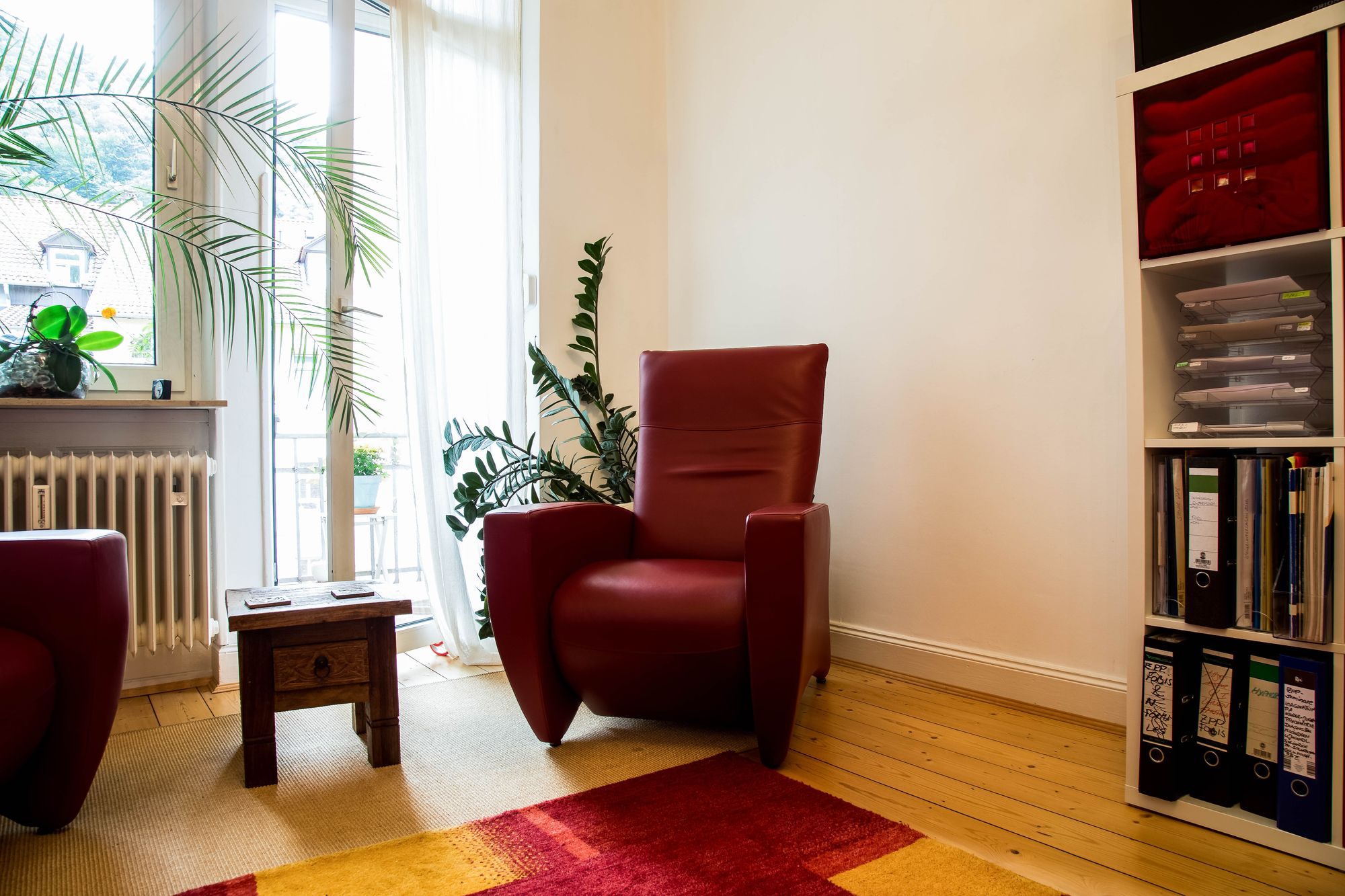 Praxiszimmer von Dipl.-Psych. Regine Scheib mit rotem Sessel am Fenster
